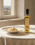 Olio d'oliva aromatizzato al tartufo bianco 250 ml Luck Pilze su un tavolo vicino alla finestra, accanto a un piatto servito